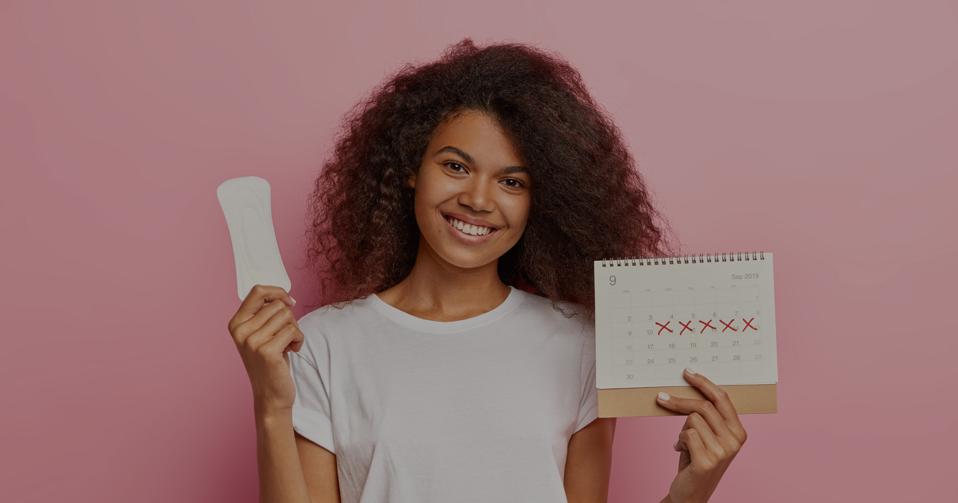 Portrait of good looking feminine girl has Afro hairstyle, holds monthly calendar, clean sanitary napkin, has menstrual cycle, happy to have good women health. People, gynecology, hygiene concept