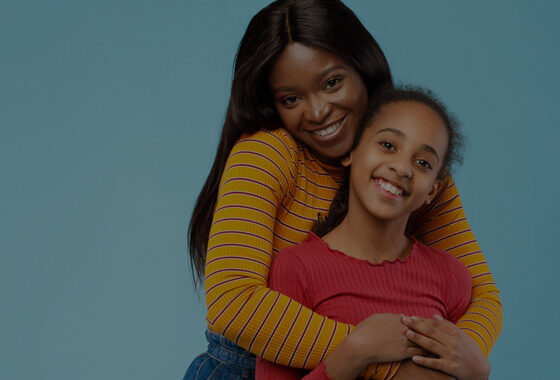 Mom and preteen daughter hugging and smiling.