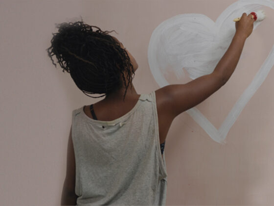 Girl painting heart image on wall, self esteem concept.