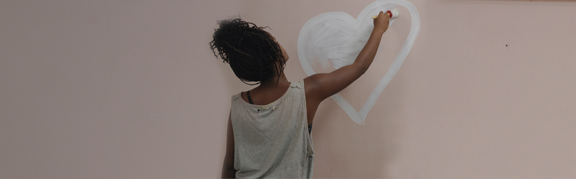 Girl painting heart image on wall, self esteem concept.