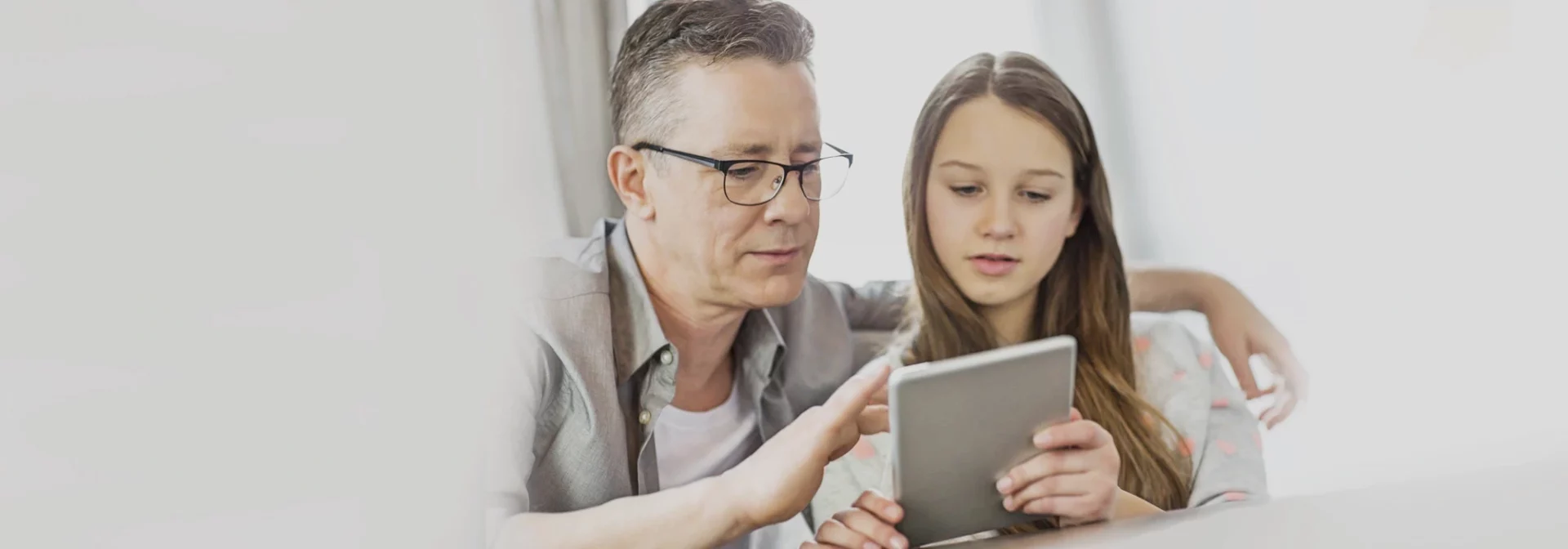 Father and teen daughter looking at tablet together. Dad showing teen safety tips.