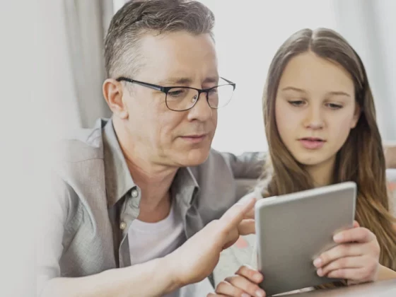 Father and teen daughter looking at tablet together. Dad showing teen safety tips.