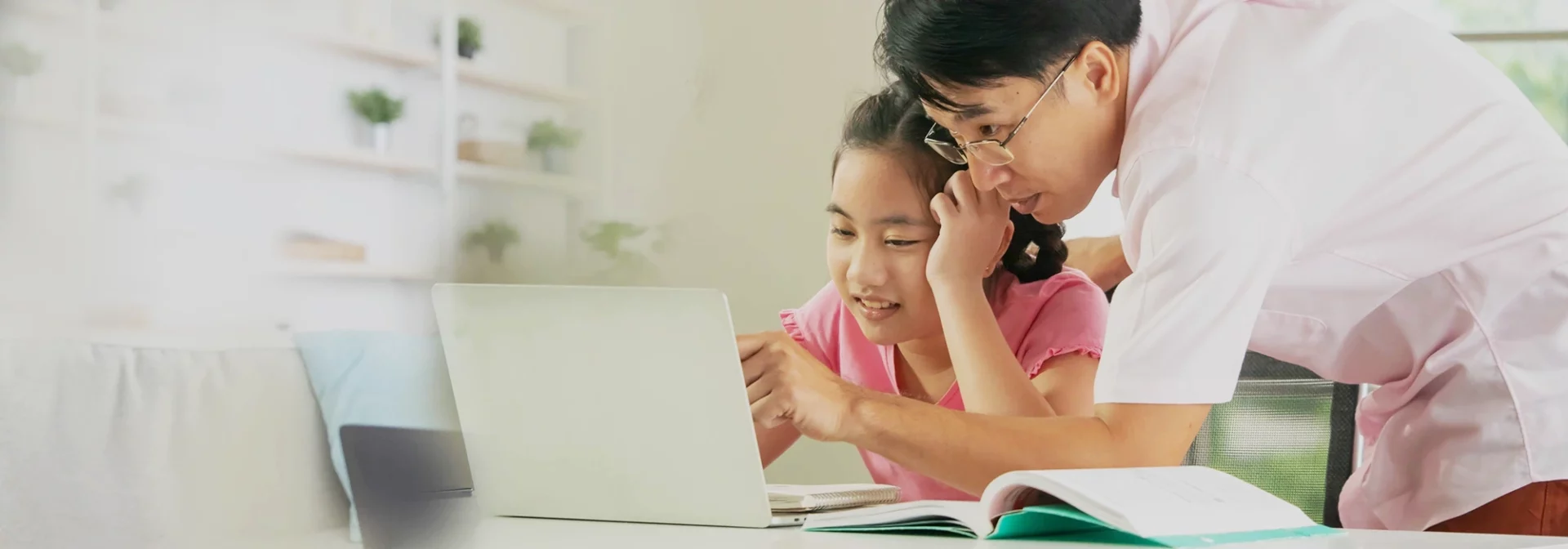 Father and preteen daughter looking at computer screen.