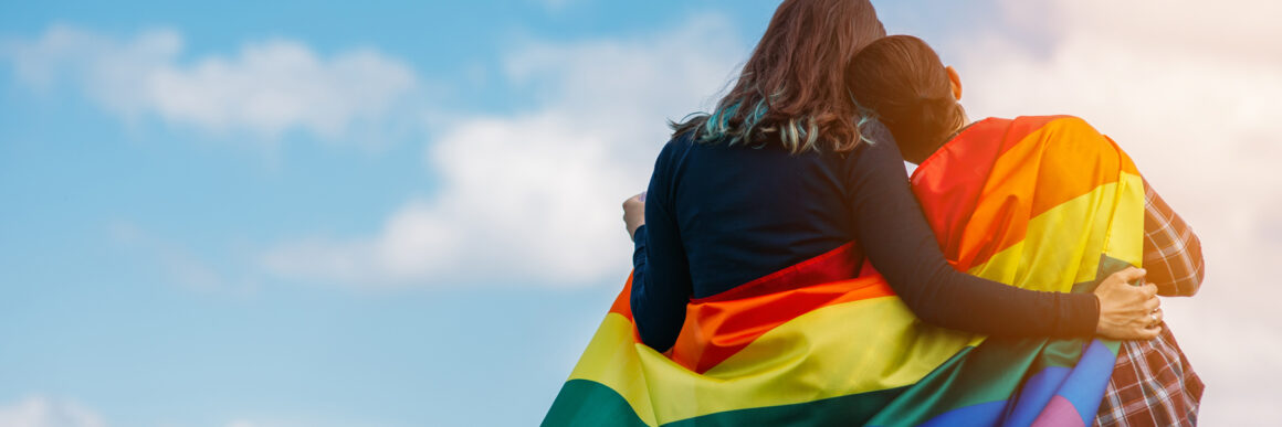 lgbtq supportive hug, mom and child hugging with LGBT flag over shoulders