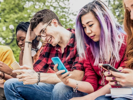 teens sitting outside on smart phones, social media and teens