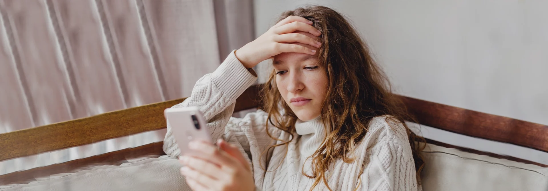 stressed out teen in bedroom looking down at phone