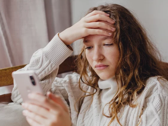 stressed out teen in bedroom looking down at phone
