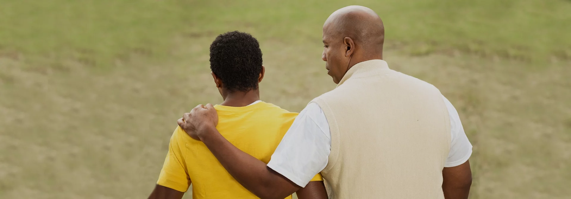 dad with arm around teen son, talking about sex with teen