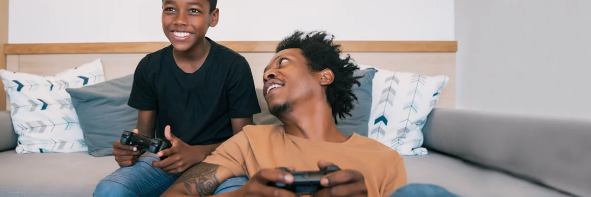 father and preteen son gaming together on couch