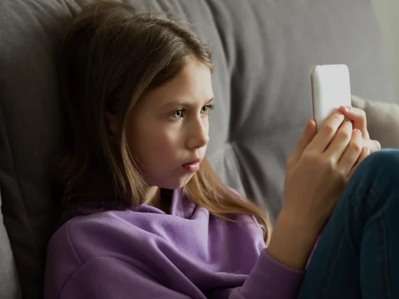 young girl with cellphone on couch looking at screen