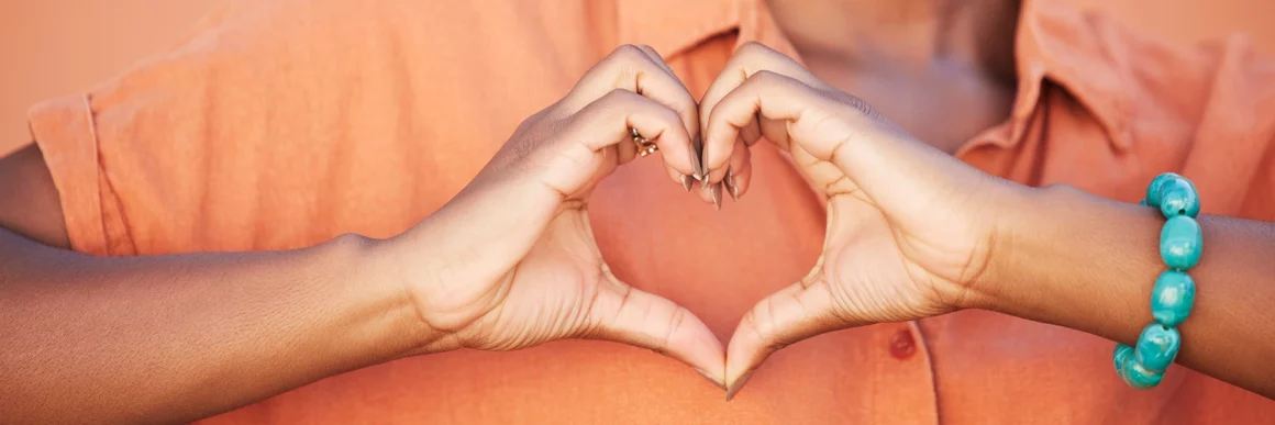 hands in heart shape over chest, bright colored shirt