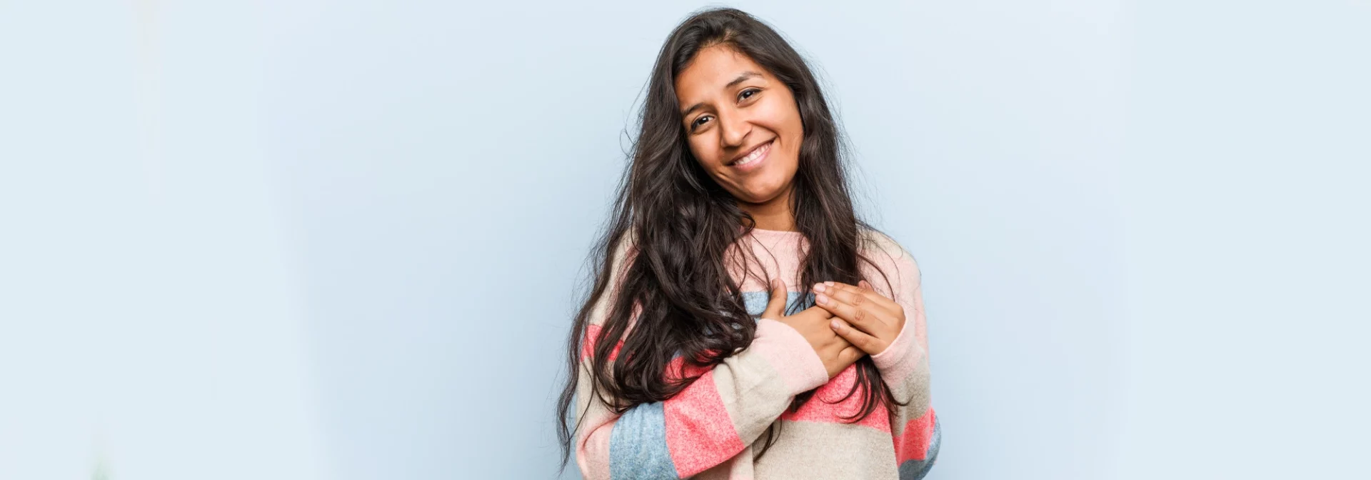 Smiling teen holding hands on heart.