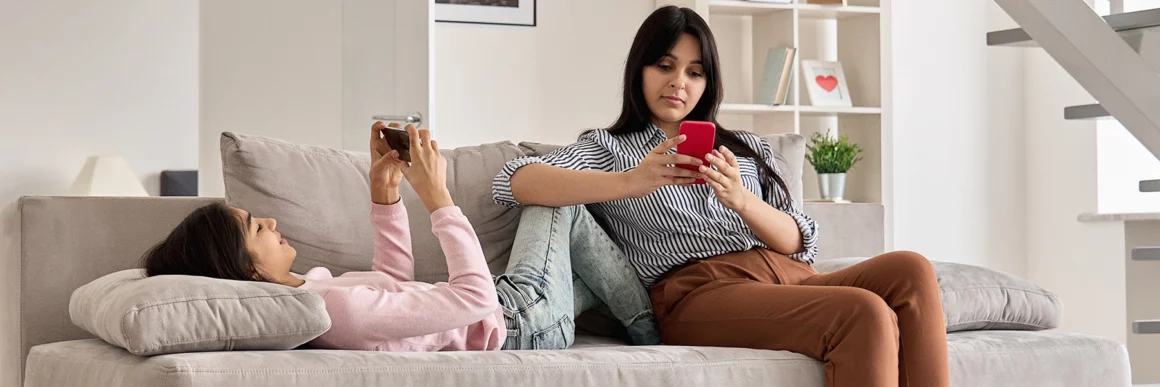 Mom and teen daughter on screens sitting on couch, mom on phone, teen on phone