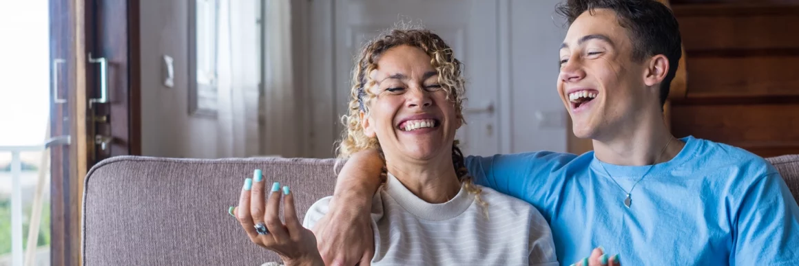 Mom and teen son laughing, talking on couch together