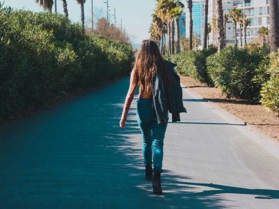 teen walking away on sidewalk outside, independent teenager
