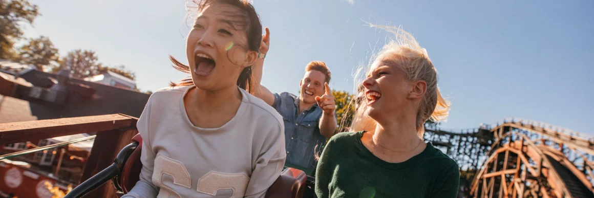 teens on top of roller coaster screaming and smiling