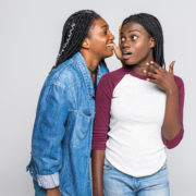 Portrait,Of,Two,Young,African,Women,Sharing,Secrets,Over,White