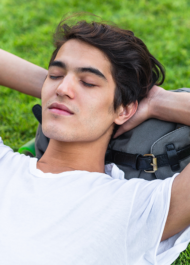 Young,Male,Skater,Resting,On,The,Grass,With,His,Eyes
