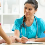 Young woman doctor talking to her teenager patient and writing down the symptoms. Concept of visit to gynecologist